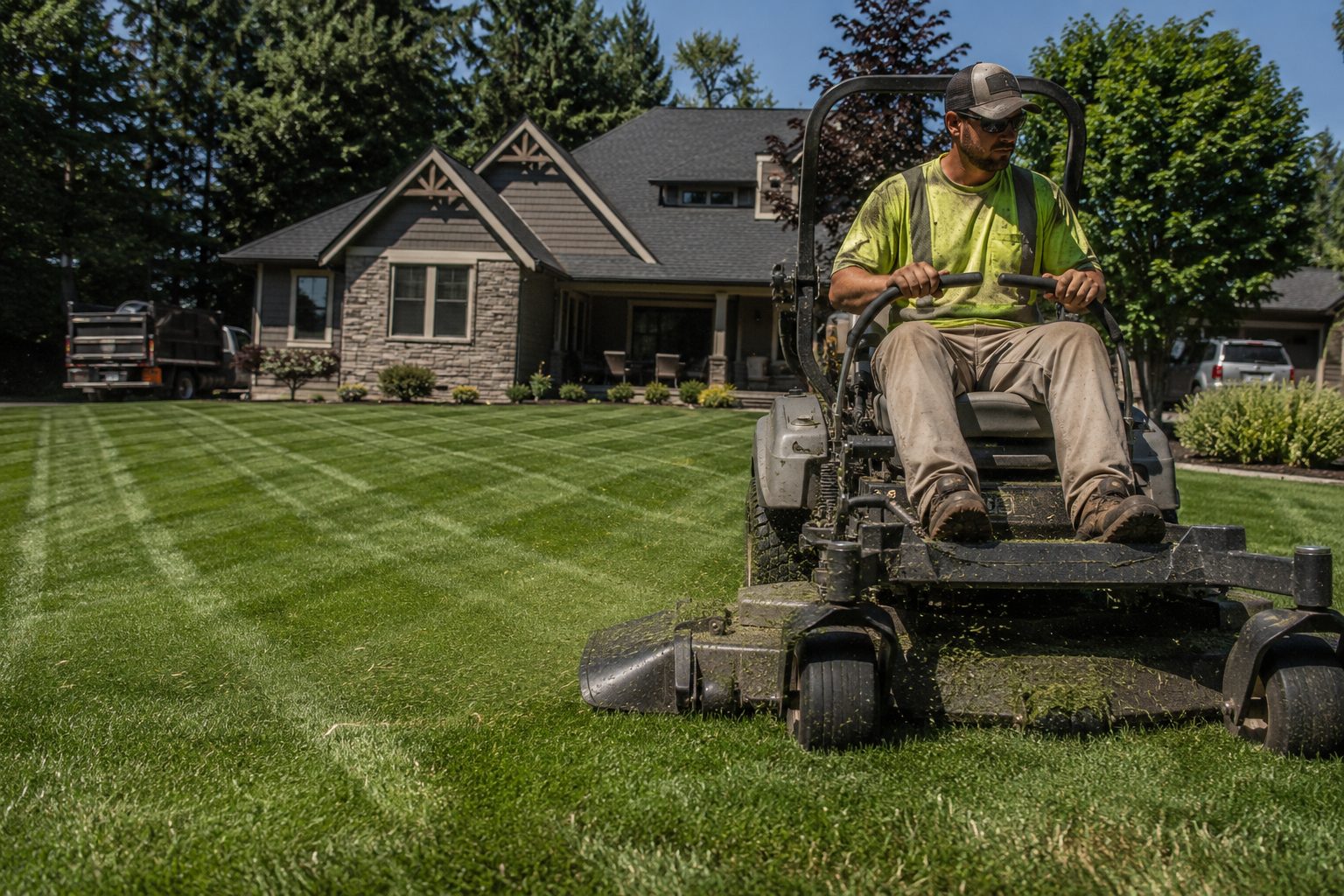 Lawn care professional mowing crisp stripes into a suburban lawn on a zero-turn mower